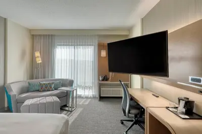 a hotel room with a bed and a flat screen tv at Courtyard by Marriott Southington in Southington