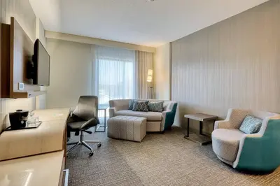 a hotel room with a desk and chairs and a living room at Courtyard by Marriott Southington in Southington