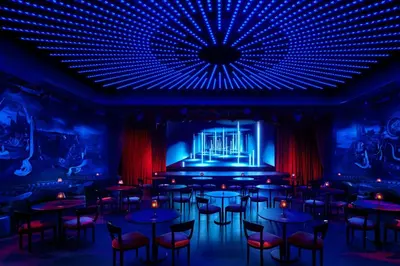 a room with tables and chairs and a stage at The Times Square EDITION New York in New York