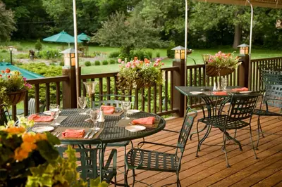 two tables and chairs on a deck with flowers at Settlers Inn in Hawley