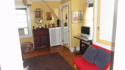 a living room with a red couch and a television at The Red Rooster in White Plains