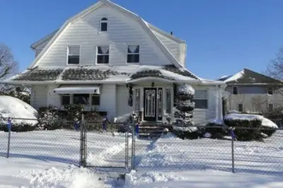 a white house with snow in front of it at The Red Rooster in White Plains