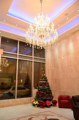 a christmas tree in a lobby with a chandelier at Asiatic Hotel - Flushing in Queens