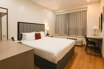 a bedroom with a large bed and a desk and a chair at Asiatic Hotel - Flushing in Queens