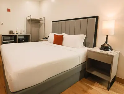 a bedroom with a large white bed and a lamp at Asiatic Hotel - Flushing in Queens