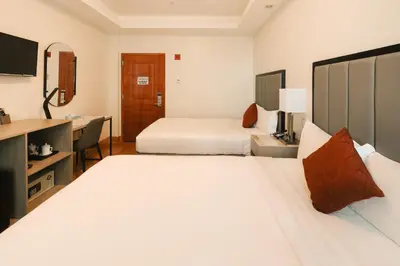 a hotel room with two beds and a desk at Asiatic Hotel - Flushing in Queens