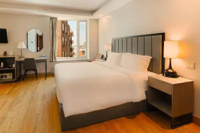 a bedroom with a large white bed and a desk at Asiatic Hotel - Flushing in Queens