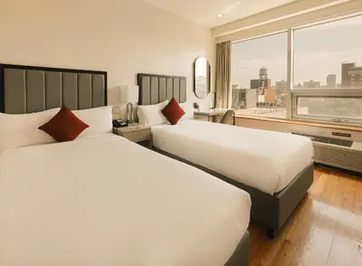two beds in a hotel room with a large window at Asiatic Hotel - Flushing in Queens