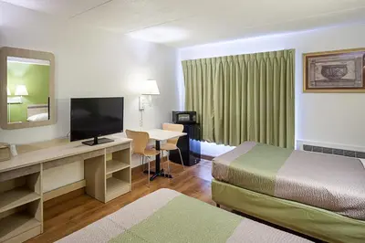 a hotel room with a bed and a desk with a television at Motel 6-Binghamton, NY in Binghamton