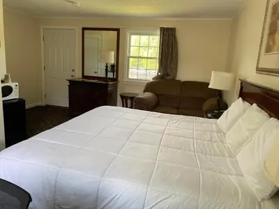 a bedroom with a large white bed and a living room at Villager Motel in Williamstown
