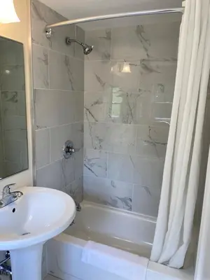a white bathroom with a sink and a shower at Villager Motel in Williamstown