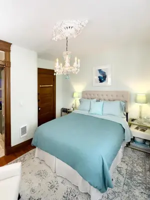 a bedroom with a blue bed and a chandelier at Shadowcrest in Fleischmanns