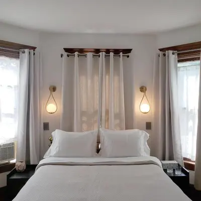 a bedroom with a bed with white pillows and windows at Shadowcrest in Fleischmanns
