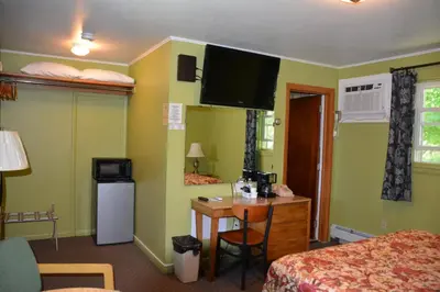 a hotel room with a bed and a desk and a television at The Village Motel in Richfield Springs