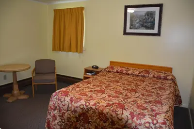 a hotel room with a bed and a table and a window at The Village Motel in Richfield Springs