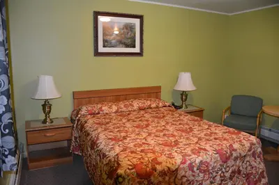 a bedroom with a bed and two lamps and a chair at The Village Motel in Richfield Springs