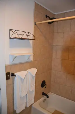 a bathroom with a tub and a sink and towels at The Village Motel in Richfield Springs