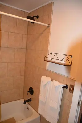 a bathroom with a tub and a shower with white towels at The Village Motel in Richfield Springs