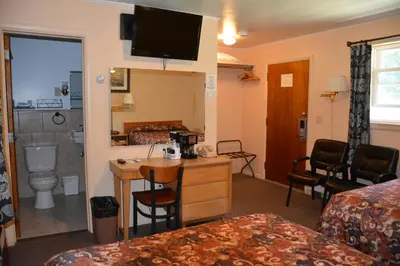 a hotel room with a bed and a bathroom at The Village Motel in Richfield Springs
