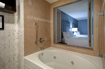 a bathroom with a tub and a bedroom with a bed at Homewood Suites by Hilton Edgewater-NYC Area in Edgewater