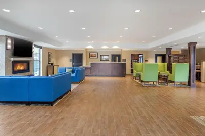 a lobby with blue and green chairs and a fireplace at Comfort Inn & Suites Schenectady - Scotia in Schenectady