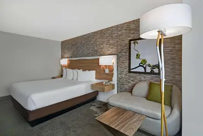a bedroom with a bed and a chair and a lamp at Hilton Hasbrouck Heights-Meadowlands in Hasbrouck Heights