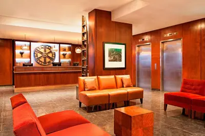 a waiting room with orange chairs and a clock at The Chelsean New York in New York