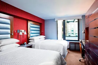 a hotel room with two beds and a red wall at The Chelsean New York in New York
