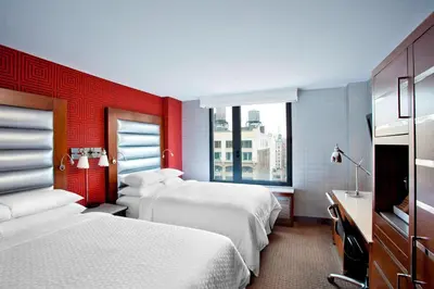 a hotel room with two beds and a red wall at The Chelsean New York in New York