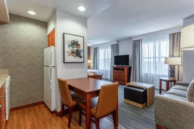 a living room with a dining room table and a kitchen at Homewood Suites by Hilton Albany in Albany