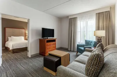 a hotel room with a couch and a bed and a television at Homewood Suites by Hilton Albany in Albany