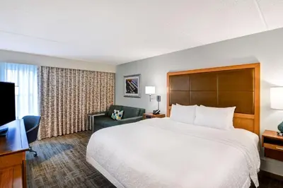 a hotel room with a large bed and a television at Hampton Inn Albany-Wolf Road in Albany