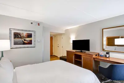 a hotel room with a bed and a desk with a television at Hampton Inn Albany-Wolf Road in Albany