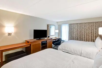 a hotel room with two beds and a desk with a television at Hampton Inn Albany-Wolf Road in Albany