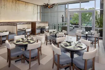 a restaurant with tables and chairs and windows at Hotel Indigo Flushing - LaGuardia in Queens
