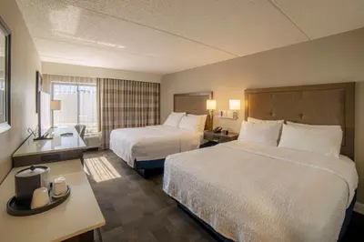 a hotel room with two beds and a desk at Hampton Inn Carlstadt At The Meadowlands in Carlstadt