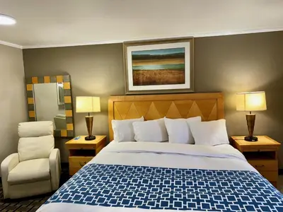 a hotel room with a bed and a chair at Rodeway Inn in Adams