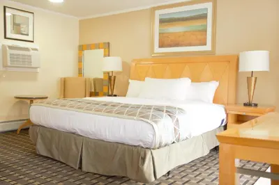 a hotel room with a large bed and two tables at Rodeway Inn in Adams