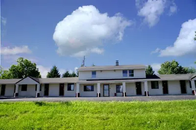 a large white building with a green field in front of it at Appalachian Motel in Vernon