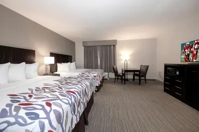 a hotel room with two beds and a desk at Red Roof Inn & Suites Newburgh - Stewart Airport West Point in New Windsor
