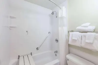 a white bathroom with a tub and a toilet and towels at Albany Plaza Hotel in Albany