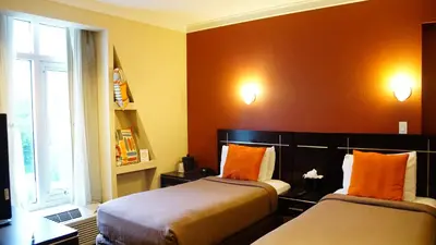 a room with two beds with orange pillows at Nesva Hotel - New York City Vista in Queens