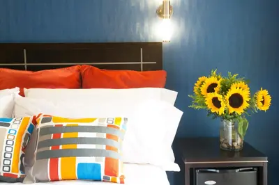 a bedroom with a bed with a vase of sunflowers on a table at Nesva Hotel - New York City Vista in Queens