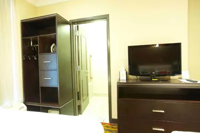 a bedroom with a tv and a dresser with a dresser at Nesva Hotel - New York City Vista in Queens