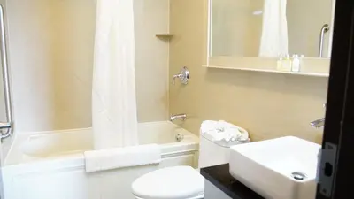 a bathroom with a white toilet and a sink at Nesva Hotel - New York City Vista in Queens