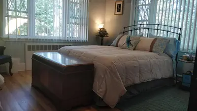 a bedroom with a bed with a table and windows at Maurrocks - A Pocono Mountains B&B in Mount Pocono