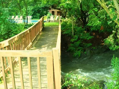a wooden bridge over a river with a table and chairs at Stay Berkshires in Williamstown