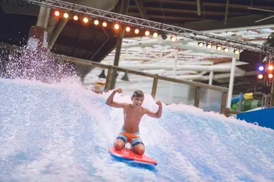 a young man riding a wave on a surfboard in a water park at The Kartrite Resort and Indoor Waterpark in Monticello