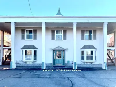a white building with a blue door and two windows at Tappan Zee Hotel in West Nyack