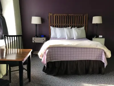 a bedroom with a large bed and a wooden table at The Inn At Stone Mill in Little Falls